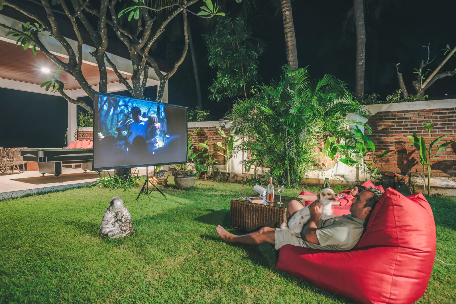 Outdoor cinema setup on the lawn at night with screen, projector, and red beanbags at Primavera Beach House.